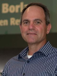 a man standing in front of a sign and wearing a blue shirt with white stripes