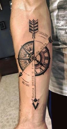 a man's arm with a compass tattoo on the forearm and an arrow in the middle