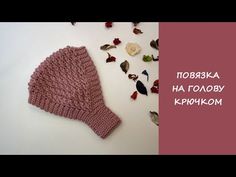 a pink knitted mitt sitting on top of a white table next to rose petals