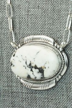 This white buffalo and sterling silver necklace was made by Zuni silversmith Kenny Calavaza. The back of the necklace is signed K. C. and Zuni, NM.Necklace: 17"Length: 1 3/8"Width: 1 7/8"Free shipping on all orders! We ship with USPS and always include tracking. All orders ship within a day of payment.Returns are accepted up to 30 days after you receive your order. Just send us a message. Our shop offers cash back or store credit. The item must be returned in new condition. Southwestern Style Necklace With Large Oval Stone, Southwestern Style Oval Necklace With Large Stone, Southwestern Oval Necklace With Large Stone, White Necklace With Large Pendant, Unique White Necklace With Large Pendant, White Pendant Necklace With Sterling Silver Clasp, Southwestern Silver Necklace With Oval Pendant, Southwestern White Oval Jewelry, Southwestern Style Oval White Jewelry