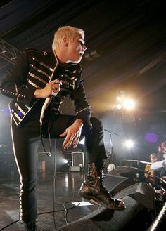 a man sitting on top of a stage while holding a microphone in his hand and singing