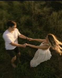 a man and woman holding hands in the grass