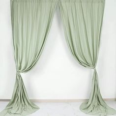 two green drapes hanging on the side of a wall