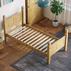 a wooden bed frame sitting on top of a hard wood floor next to a potted plant