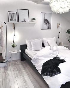 a bedroom with white bedding and pictures hanging on the wall, along with wooden flooring