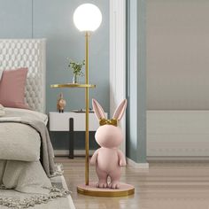 a pink bunny lamp sitting on top of a wooden floor next to a bed in a bedroom