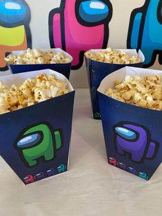 four blue boxes filled with popcorn sitting on top of a white table covered in paper