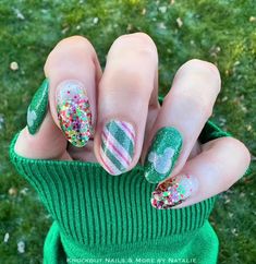 a person with green and white nail polish on their nails