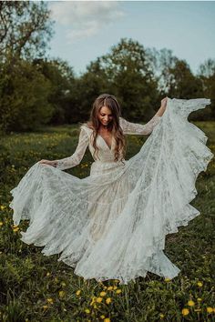 a woman in a white dress is standing in the grass with her arms spread out