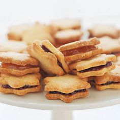 a white cake plate topped with cookies and jam filled pastries on top of each other