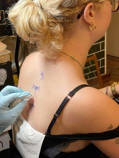 a woman with tattoos on her back is getting inked by a tattoo artist at the same time