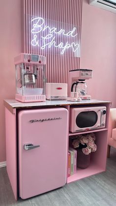 a pink refrigerator freezer sitting inside of a kitchen next to a neon light sign