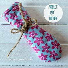 a blue and pink flowered bag tied up to a white wooden wall with the words skillet pot holder on it