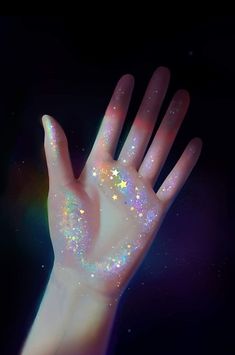 a person's hand with holographic stars painted on it, against a black background