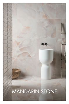 a white toilet sitting in a bathroom next to a wall mounted faucet and tiled walls