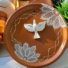 a white bird figurine sitting on top of a brown plate next to other decorations