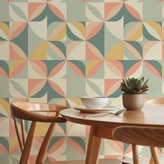 a table with two chairs and a potted plant sitting on it in front of a colorful wallpaper