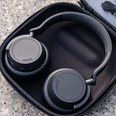 an open case with headphones in it on the ground next to a pair of ear buds