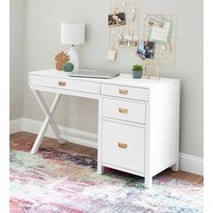 a white desk with two drawers and a lamp on it next to a rug in a room