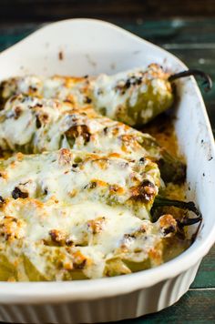 a casserole dish filled with green peppers covered in cheese and seasoning sitting on a wooden table