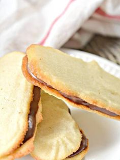 three cookies with chocolate filling on a white plate