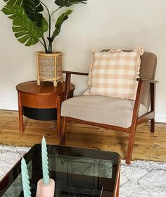 a living room with two chairs and a coffee table in front of a potted plant