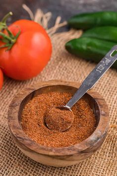 a wooden bowl filled with taco seasoning next to tomatoes