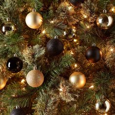 a christmas tree is decorated with black and gold baubes, lights and ornaments