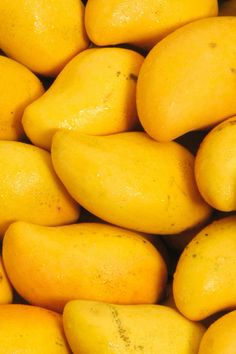 a pile of yellow mangoes sitting next to each other