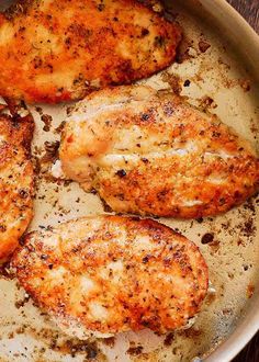 four pieces of chicken in a pan with seasoning on the top and bottom half