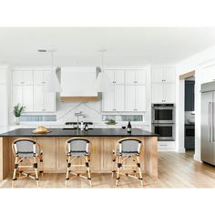 two chairs sit in front of an island in the middle of a kitchen with white cabinets and stainless steel appliances