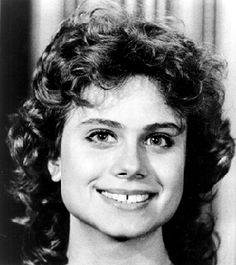 an old black and white photo of a woman with curly hair smiling at the camera