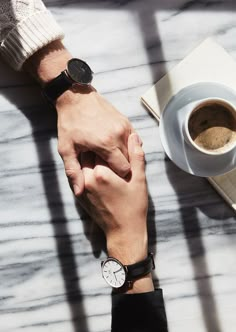 two people holding hands over a cup of coffee