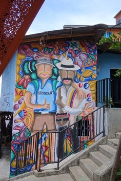 a painting on the side of a building with stairs leading up to it and a man holding a paper in his hand