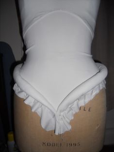 a mannequin wearing a white top with ruffles on it's sides