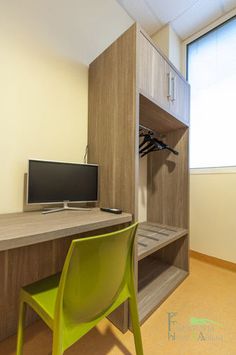 a desk with a computer monitor on top of it and a green chair in front of it