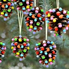 pine cone ornaments hanging from a tree with colorful balls on them and beads in the middle