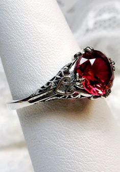 Red Ruby Ring (Natural or Simulated)  Knight Round Design#162 Custom-Made Here we have a Victorian/Deco reproduction ring in sterling silver filigree with a Simulated red ruby gemstone or a Natural Color/Heat Ruby solitaire. (See the labeled picture in the set for the Natural Ruby option, Natural Ruby, Si1 to I3 clarity, color/heat treated). This full cut round cut red ruby gem is 8mm in diameter and is approximately 2ct. This ring also sits 7mm off the finger. The inside of the band is marked 9 Red Ruby Ring, Star Ruby Ring, Art Deco Filigree, Filigree Jewelry, Knight Art, Bronze Ring, Luxury Rings, Star Ruby, Sterling Silver Filigree