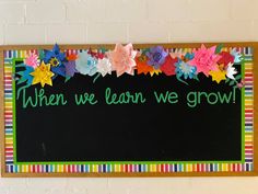 a sign that says when we learn we grow with paper flowers on the bottom and below it