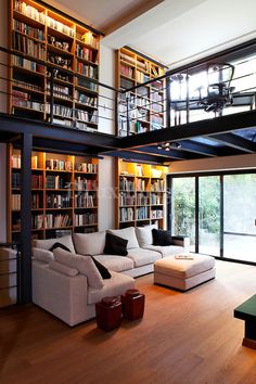 a living room filled with lots of furniture and bookshelves next to a window