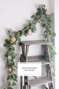 a wooden shelf with flowers on it next to a wall mounted planter and ladder