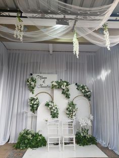 the wedding stage is decorated with white flowers and greenery