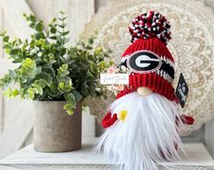 a knitted green bay packers gnome sitting on top of a table next to a potted plant