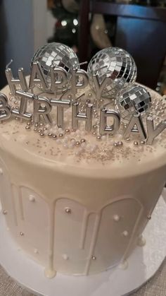 a white birthday cake with silver decorations on top