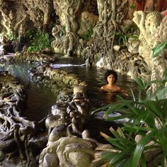 a man swimming in a pool surrounded by rocks and plants