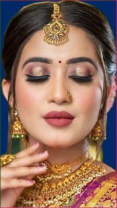 a woman with makeup and jewelry on her face, looking down at the camera while wearing gold