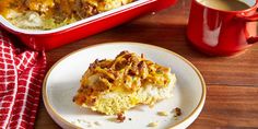 a piece of casserole on a plate next to a cup of coffee and a red mug