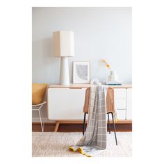 a living room with white furniture and a plaid blanket on the chair next to it