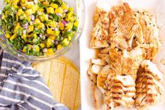 chicken, corn and salad on a plate next to a white tray with a blue striped dish towel