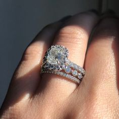 a woman's hand with a diamond ring on top of her finger and the other hand holding an engagement ring